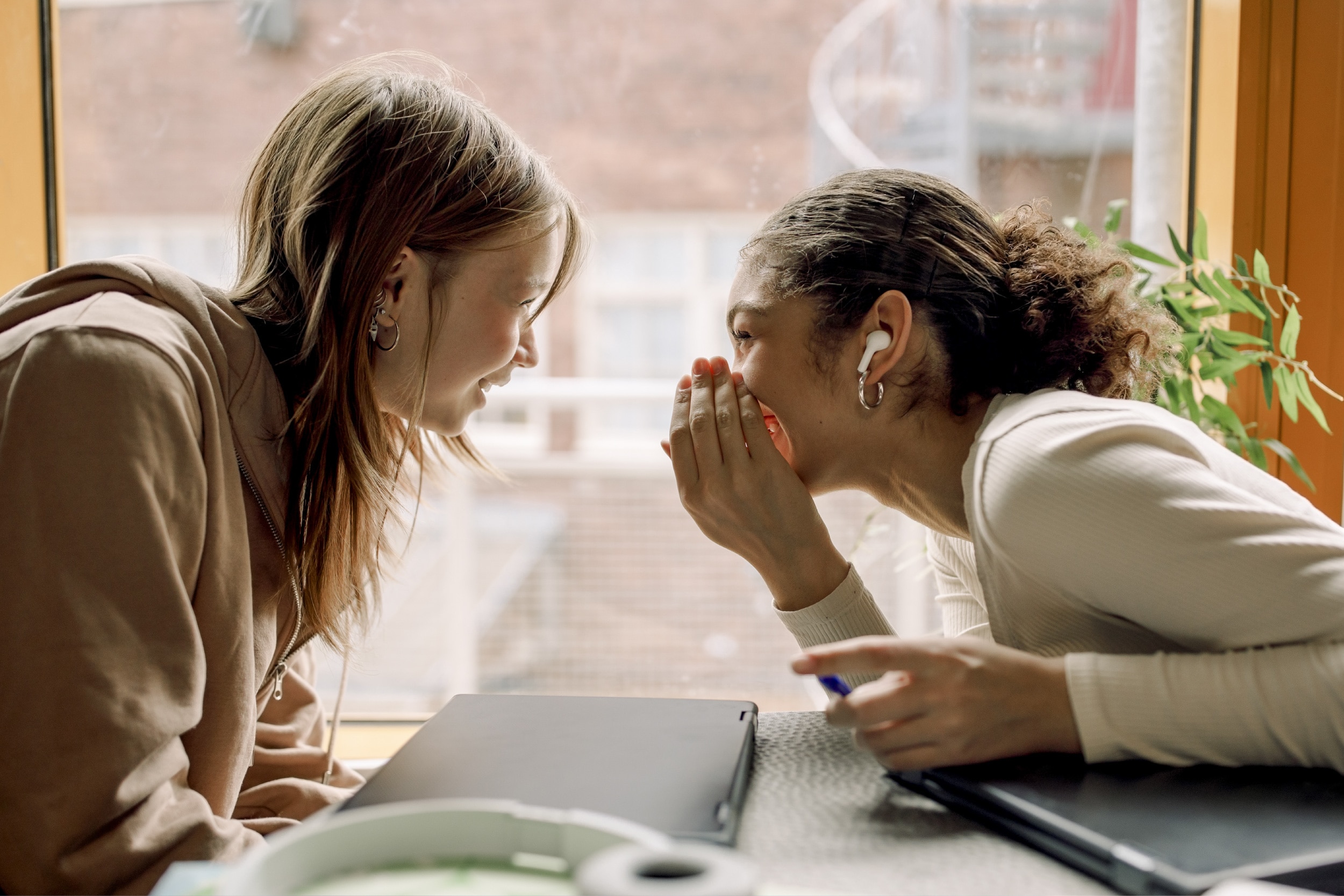 Two female students whispering to each other