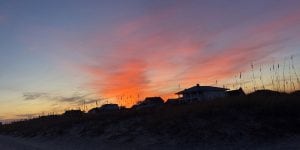 A silhouette of a row of beach houses at sunset.