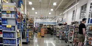 A grocery store with shelving featuring various grocery items and yellow sale price flyers.