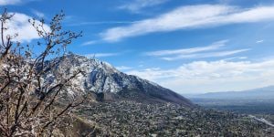 A view of a mountain in Utah during the day with blue sky and a few white clouds.