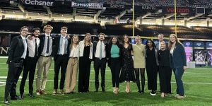 A group of fourteen college student interns standing on the football field in the Superdome in New Orleans.