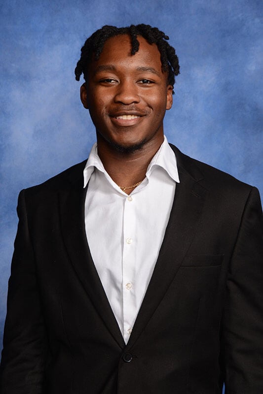 Blog author Arnold has short braids and is wearing a dark blazer over a white shirt.