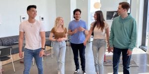 Five college students in a college building walking together and talking.