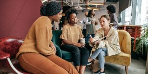 Two college interns meeting with a manager in a casual office setting.