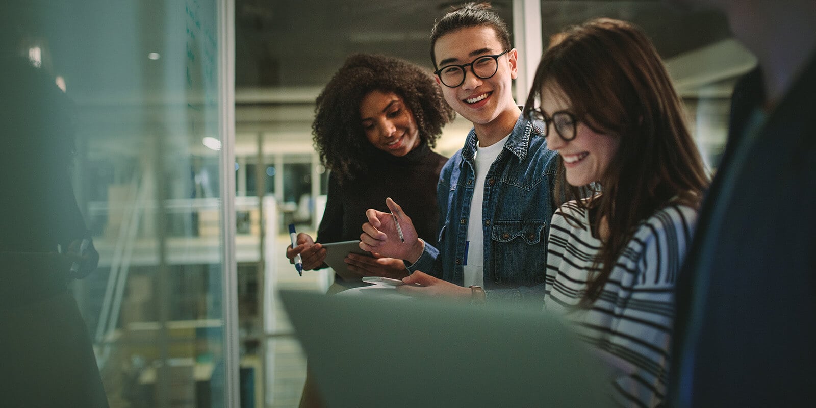 Students standing at a white board laughing and collaborating.