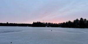 A snowy landscape at sunset with pink clouds in the distance.