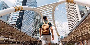 A person wearing a backpack walks through an archway between two tall buildings.