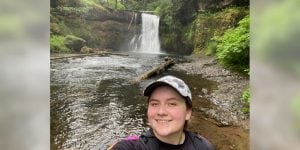 A selfie of blog author Jordan wearing a baseball hat and standing in front of a waterfall.