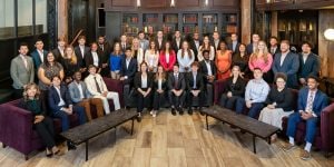 A large group of college interns posing in a business library room.