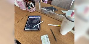 A student’s desk with a tablet, cup, pens and other accessories.