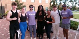 A group of seven college students standing outside of a residence hall.