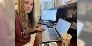 Blog author Tatum sits at a desk with two computer screens open to accounting programs.