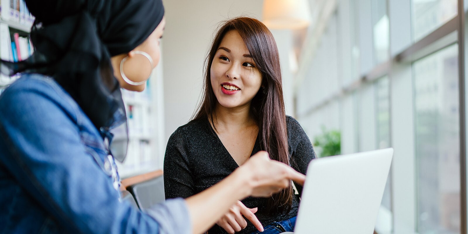 Two students discussing content on the laptop in front of them