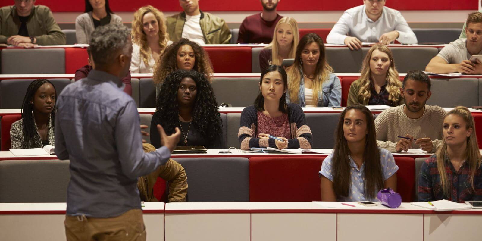 instructor teaching in front of a group of students in a auditorium setting