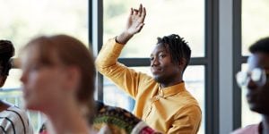 Man raising his hand in a college classroom 