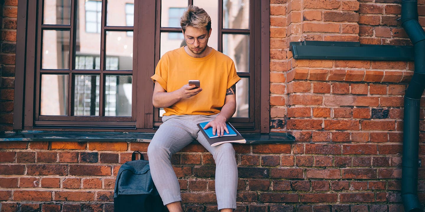 A person sitting at the windiw and looking at the phone