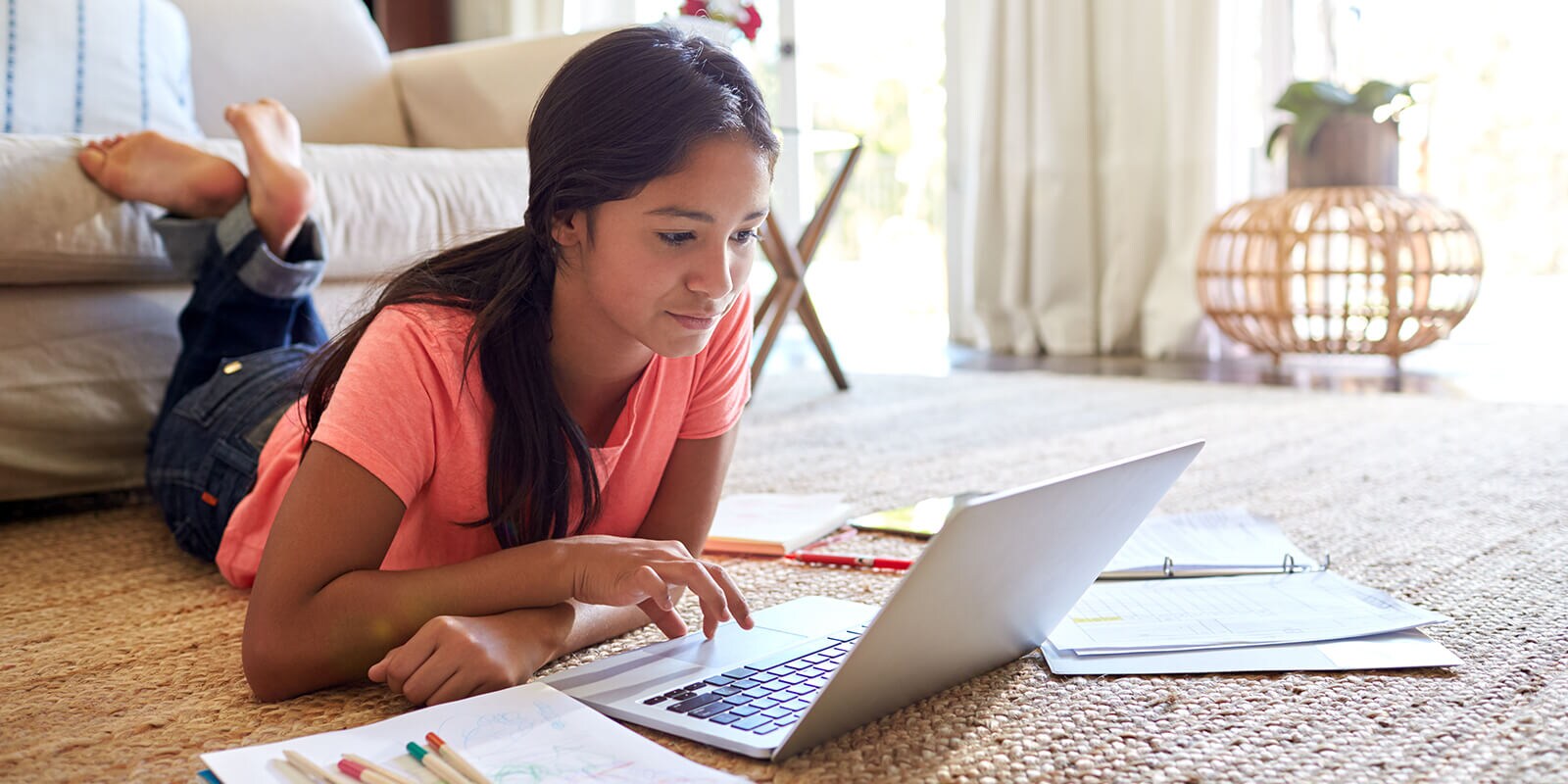 Woman laying down on floor and looking at computer, with material on the floor