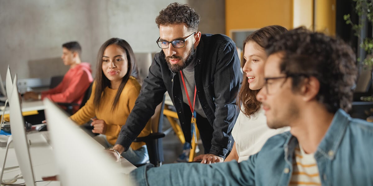 Instructor with students looking at computer monitors