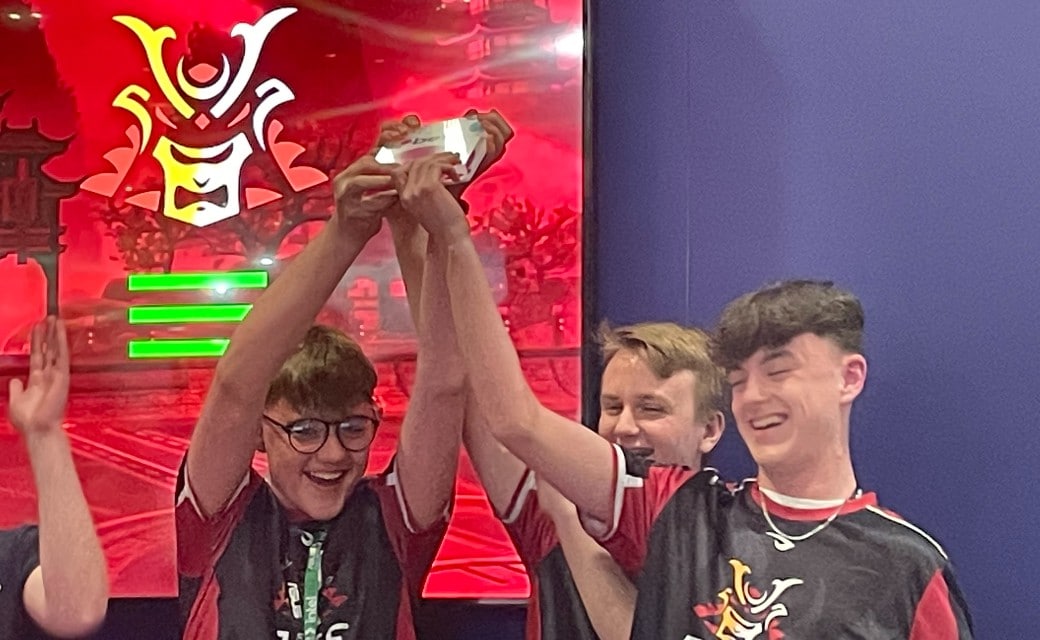 QMC college students holding a trophy aloft