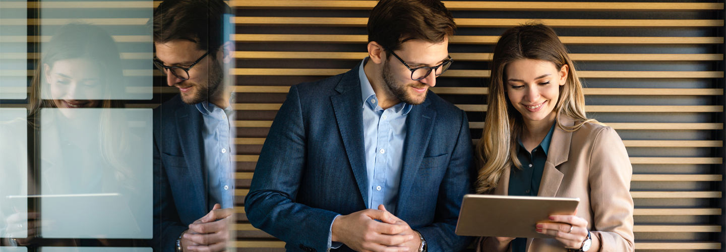 وقف اثنان من زملائه في العمل معا يبتسمان وينظران إلى جهاز لوحي معا