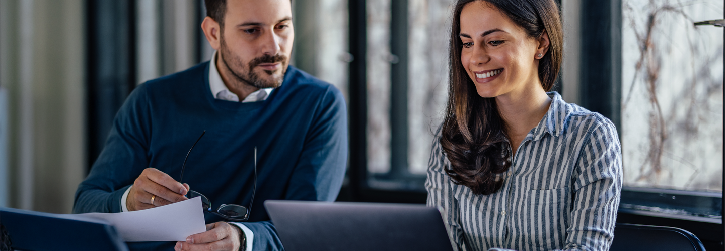 two business people sat together in a meeting both looking at a laptop