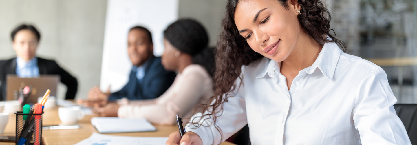 オフィスのテーブルに座ってメモを書いているビジネスウーマン