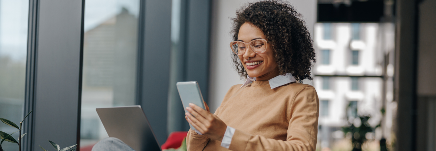 電話で笑顔のビジネスウーマンが、ラップトップを膝に乗せてオフィスに座っていました