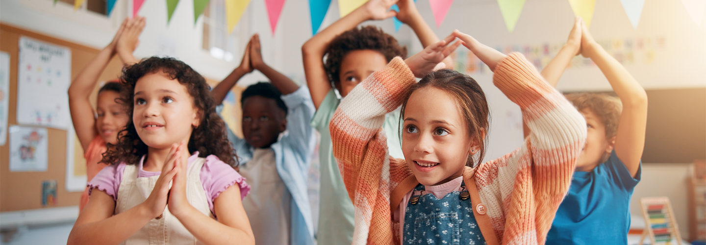 Children stood in a class with their hands up in a activity