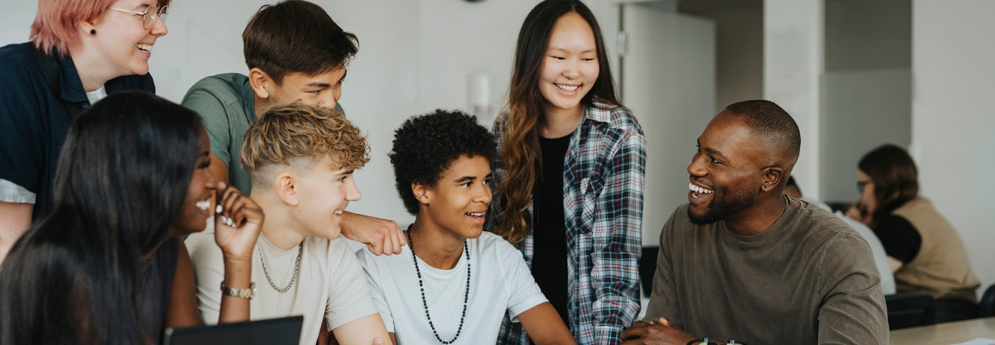 A group of students at a table talking to their teacher