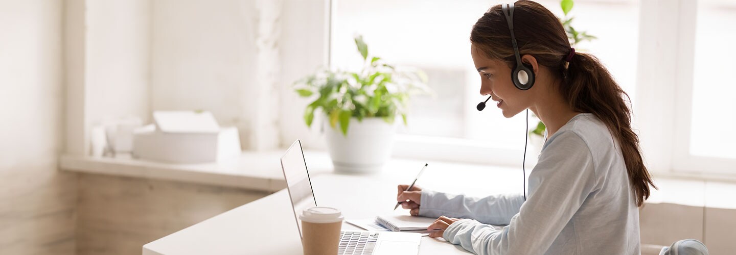 A woman making notes during an online meeting