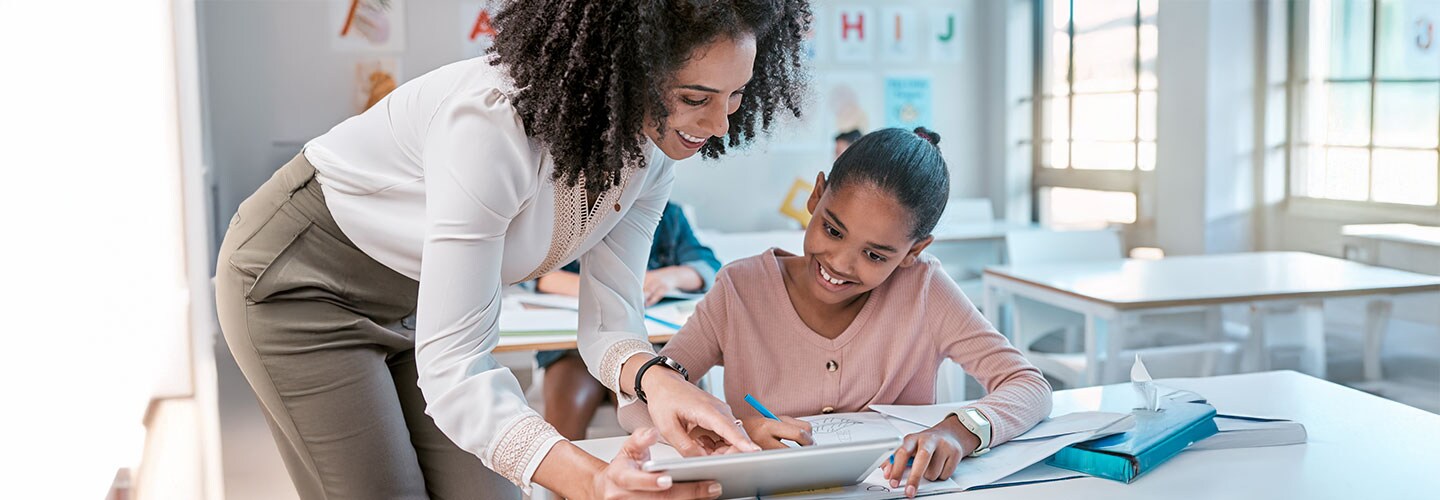 Female teacher using tablet with pupil